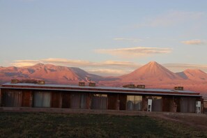 A single-story building with a flat roof, multiple windows, and a door. - Eltoconar atacama (San Pedro de Atacama)