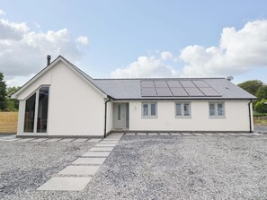 A single-story building with a sloped roof, a door, and a window. - Kingfisher (Llanbedr)