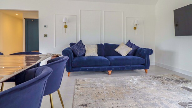 Una sala moderna con un sofá azul, una mesa de comedor y sillas.