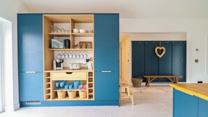 Una cocina moderna con armarios azules, un banco de madera y una decoración con forma de corazón en la pared.