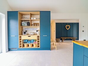 A modern kitchen with blue cabinetry, a wooden bench, and a heart-shaped decoration on the wall. - Kingfisher (Llanbedr)