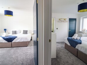 A hotel room with two beds, a wardrobe, a desk, a mirror, and a door. - Kingfisher (Llanbedr)
