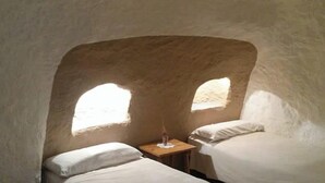 Una stanza con due letti, un comodino e una finestra.