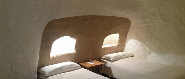 A room with two beds, a small table, and a window.