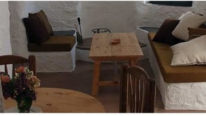 Una stanza accogliente con un tavolo di legno, un divano con cuscini, una sedia e un tavolino con un vaso di fiori.
