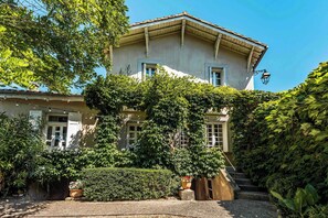 Ein zweistöckiges Gebäude mit Garteneingang, einer Treppe und einem sichtbaren Fenster.