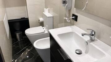 A modern bathroom with a white sink, a bidet, and a toilet.