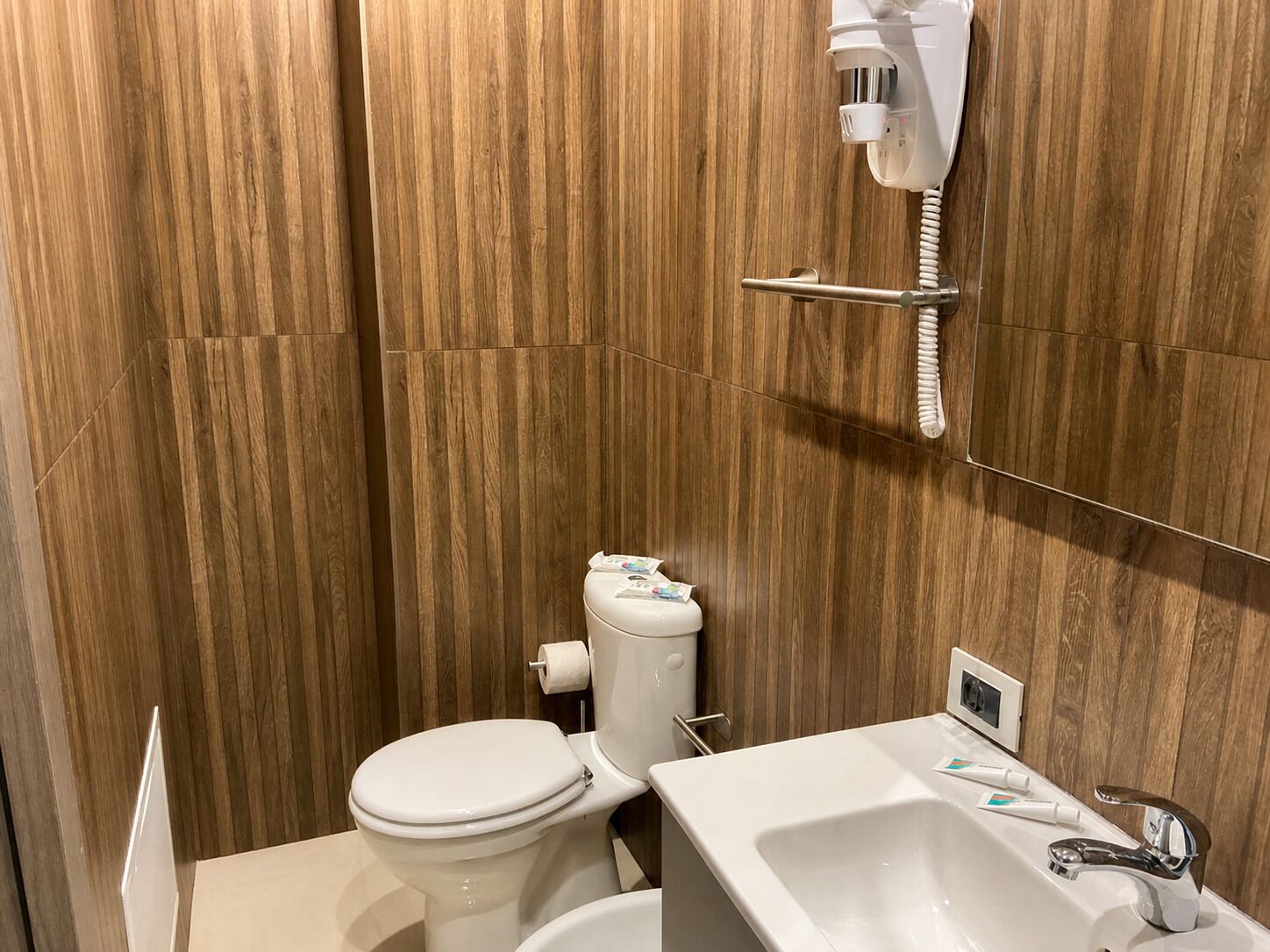A bathroom with a toilet, bidet, sink, and a telephone.