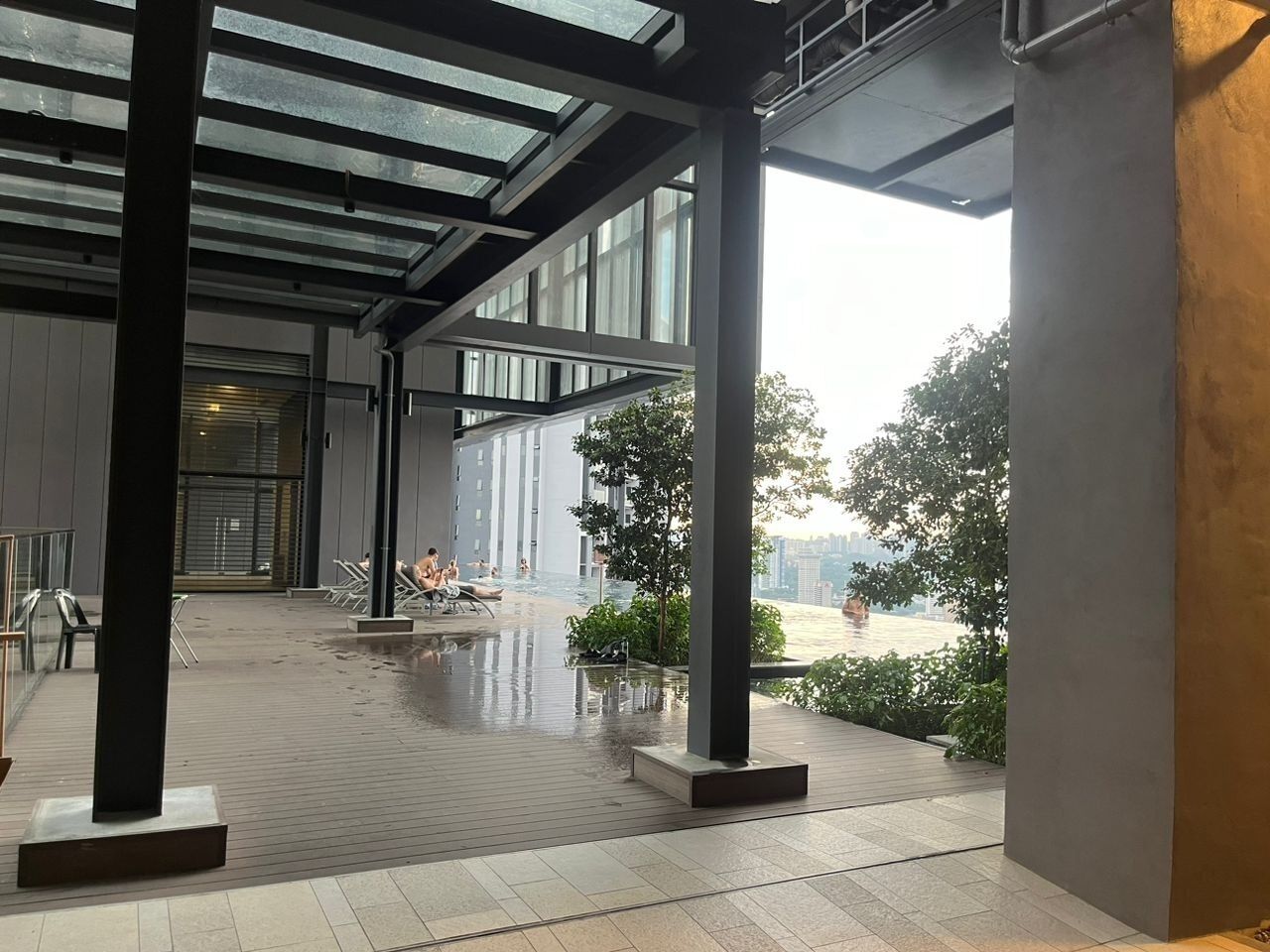 Área externa coberta com piscina, área de estar e vista para a paisagem urbana.