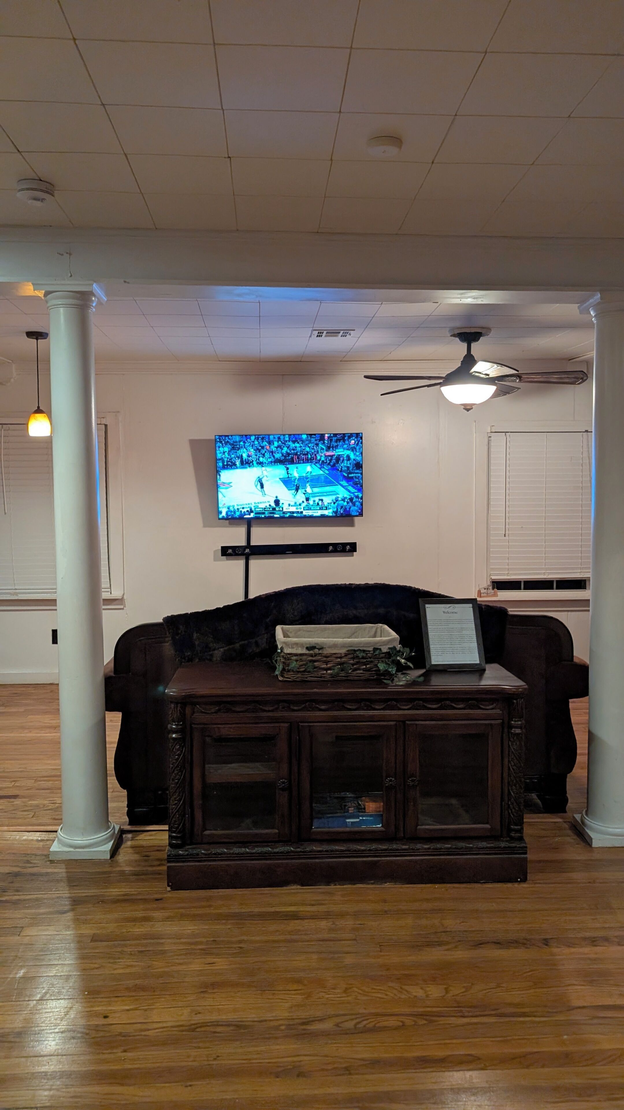 Una sala de estar con un televisor, un mueble de madera oscura y un ventilador de techo.