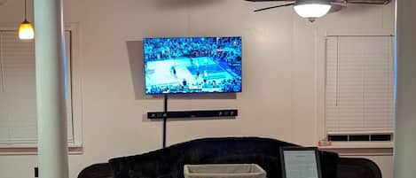 Una sala de estar con un televisor, un mueble de madera oscura y un ventilador de techo.
