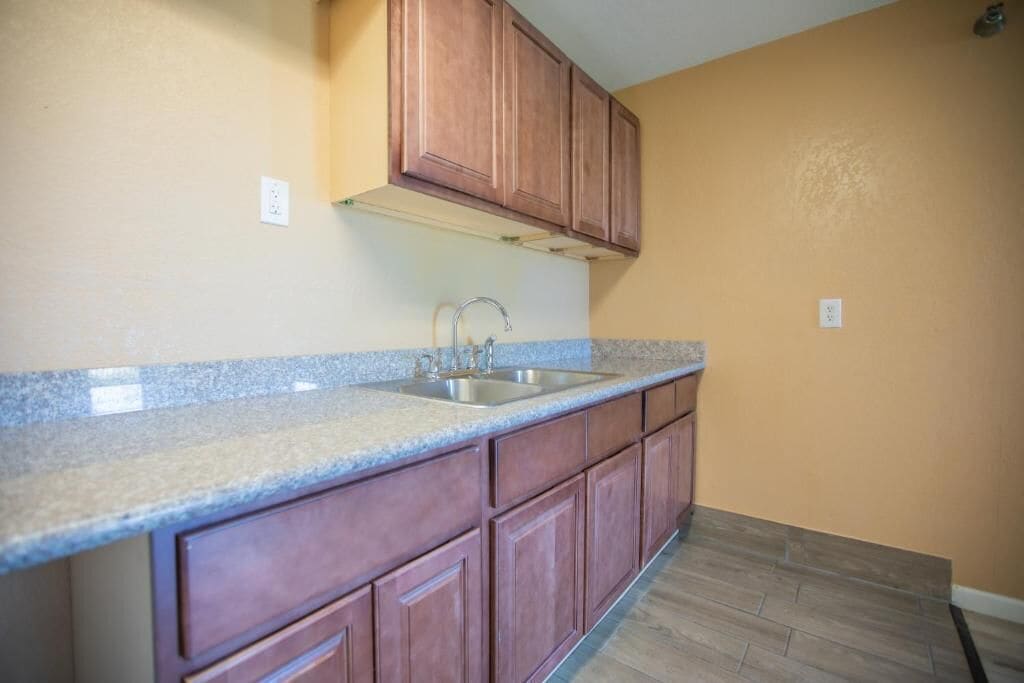 A kitchen with wooden cabinets, a granite countertop, and a stainless steel sink.