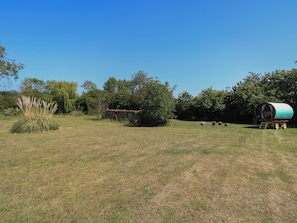 A rural landscape with a covered wagon, a small building, and a field. - The Bowtop Gypsy Caravan (Eye)