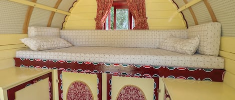 A cozy interior with a bench seating area, a window with curtains, and decorative panels.