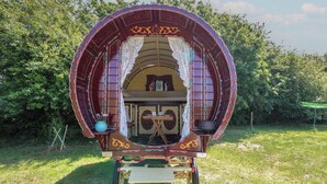 Un carro cubierto con una pequeña zona cerrada, una mesa y una silla.