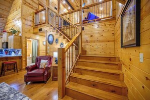 Ein Holzblock-Interieur mit Treppe, Essbereich und Wohnzimmer mit einem roten Ledersessel.