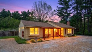 A single-story house with a front porch, a chimney, and a gravel driveway.