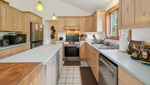 A modern kitchen with wooden cabinets, stainless steel appliances, and a large island.