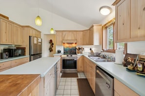 A modern kitchen with wooden cabinets, stainless steel appliances, and a large island.