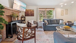 A living room with a fireplace, a sofa, a coffee table, and a TV mounted on the wall.