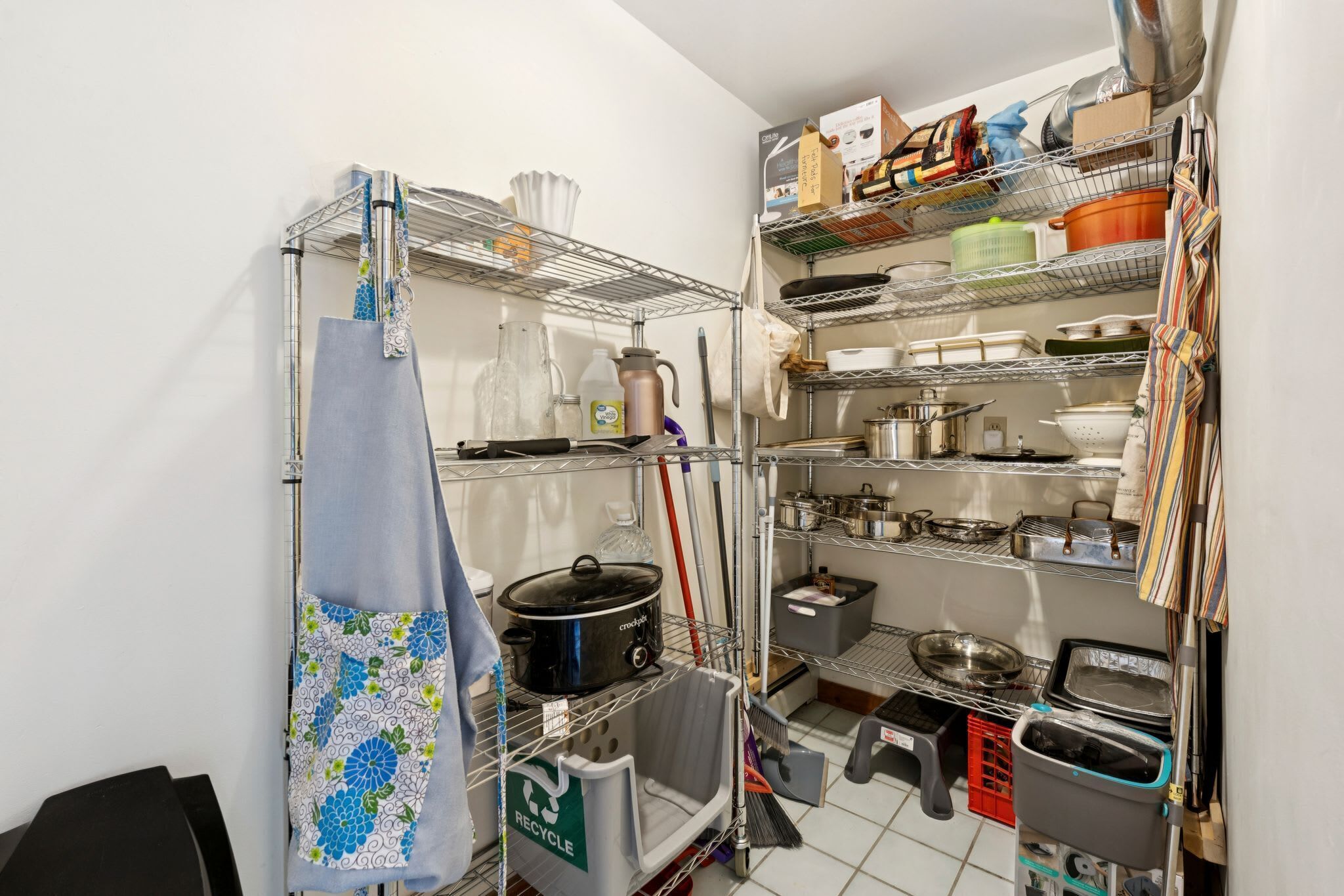 A kitchen with metal shelves, a stove, and various kitchen utensils.