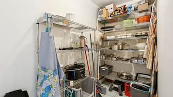 A kitchen with metal shelves, a stove, and various kitchen utensils.