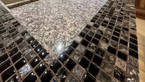 Una cocina con encimera de granito, electrodomésticos de acero inoxidable y salpicadero de azulejos.