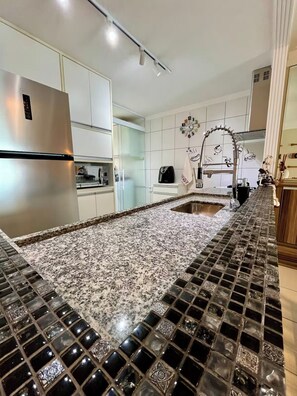 A kitchen with a granite countertop, stainless steel appliances, and a tiled backsplash.