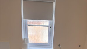 Ein Badezimmer mit Toilette, Fenster, Waschbecken und Mülleimer.