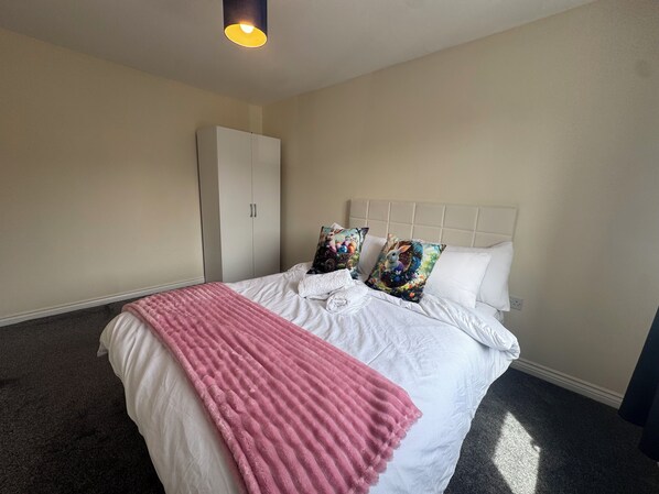 A bedroom with a bed, a wardrobe, and a ceiling light.