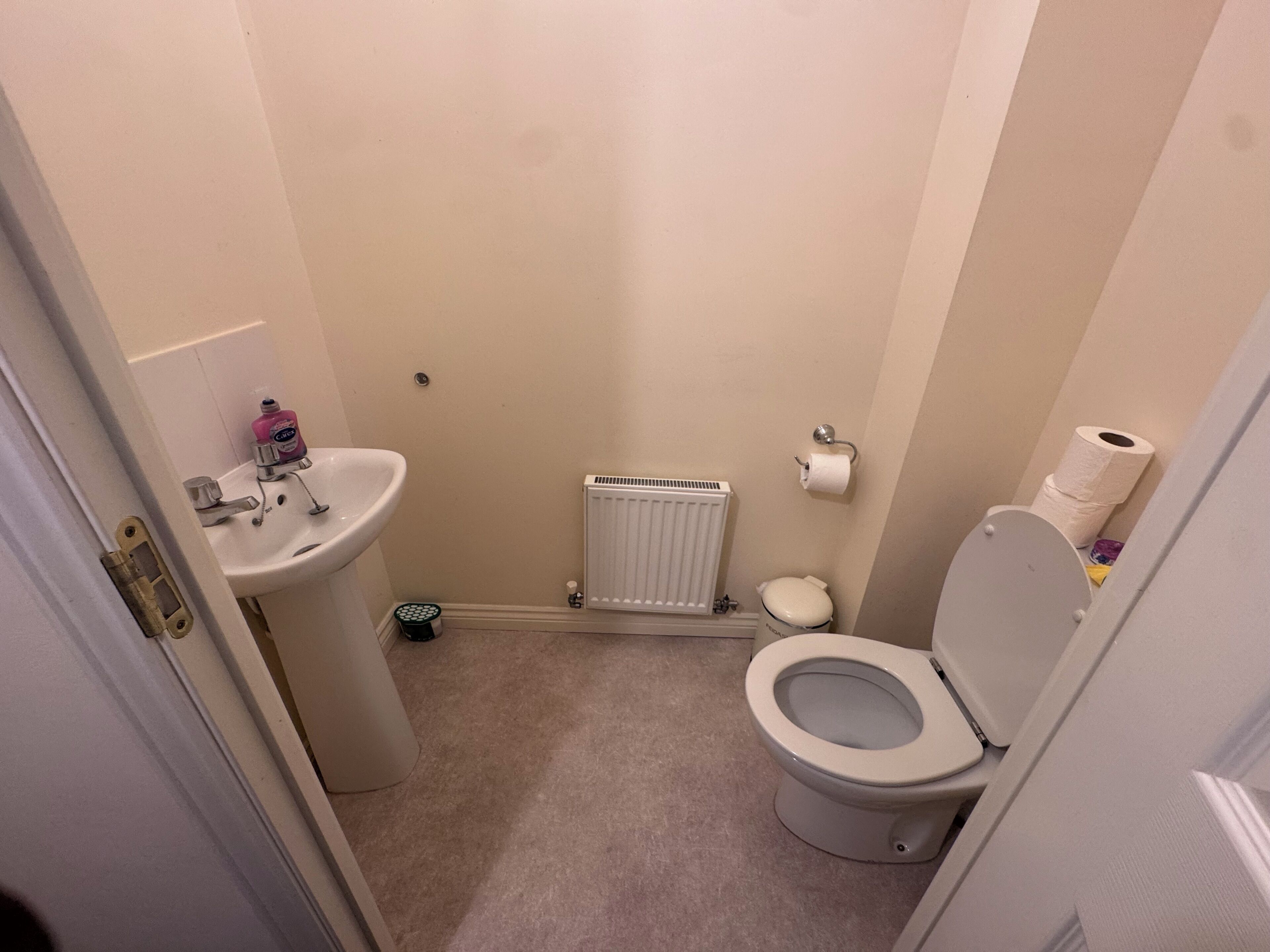A small bathroom with a toilet, sink, and radiator.