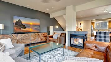 A modern living room with a fireplace, leather sofas, a glass coffee table, and a large painting on the wall.