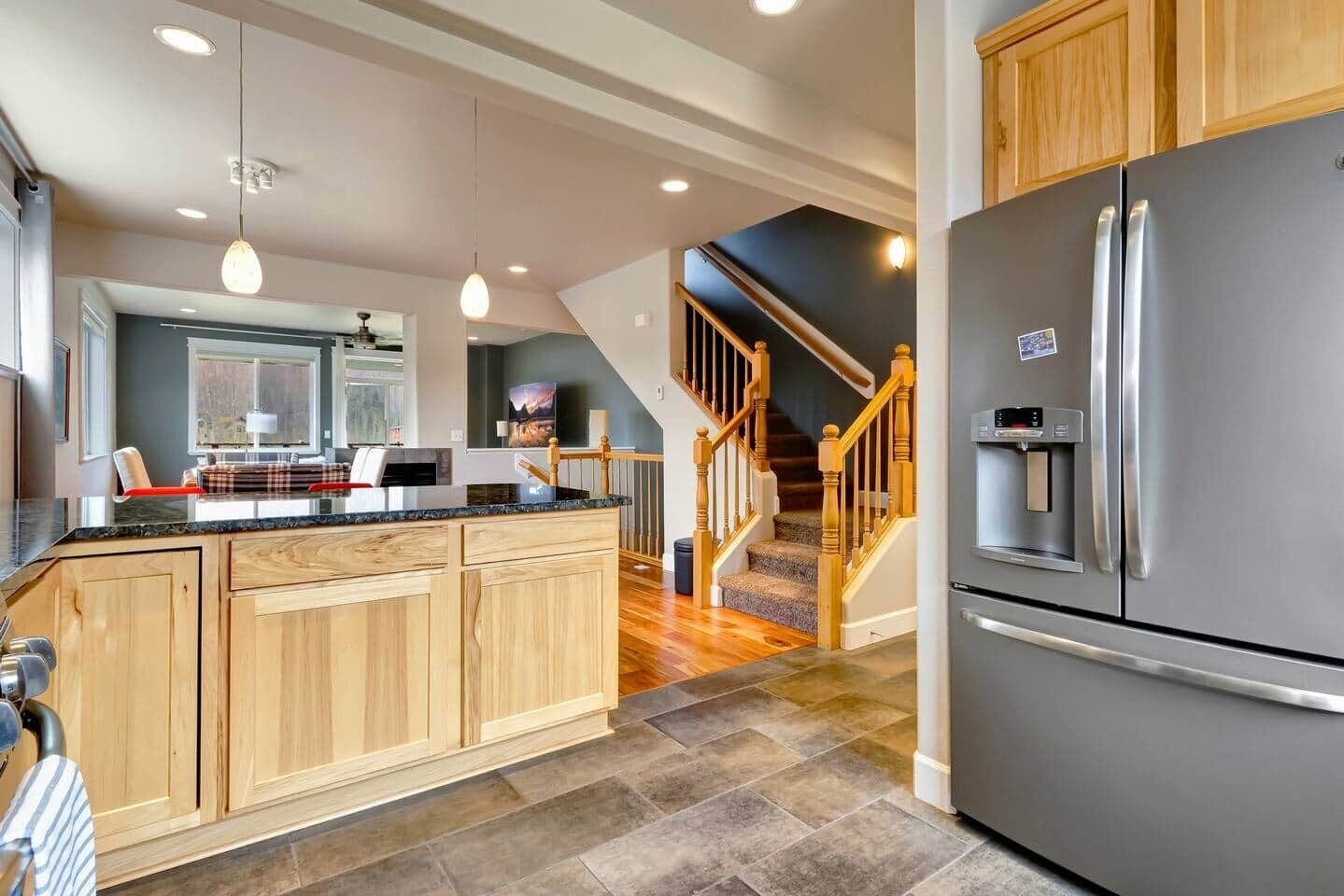 A modern kitchen with wooden cabinets, a stainless steel refrigerator, and a built-in oven.