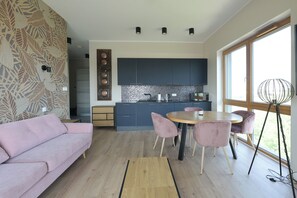 A modern kitchen with dark cabinets, a round table, and pink chairs. - Apartment Aurora by Q4 Apartments  (Gdańsk)