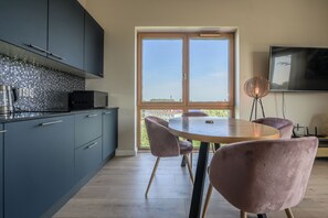 A modern kitchen with dark cabinets, a tiled backsplash, and a large window. - Apartment Aurora by Q4 Apartments  (Gdańsk)