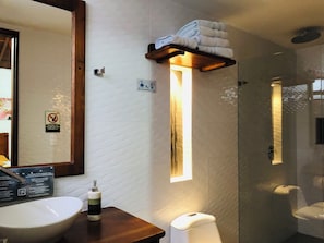 Une salle de bain équipée d’un lavabo, d’un porte-serviettes, de toilettes et d’une douche à parois en verre.