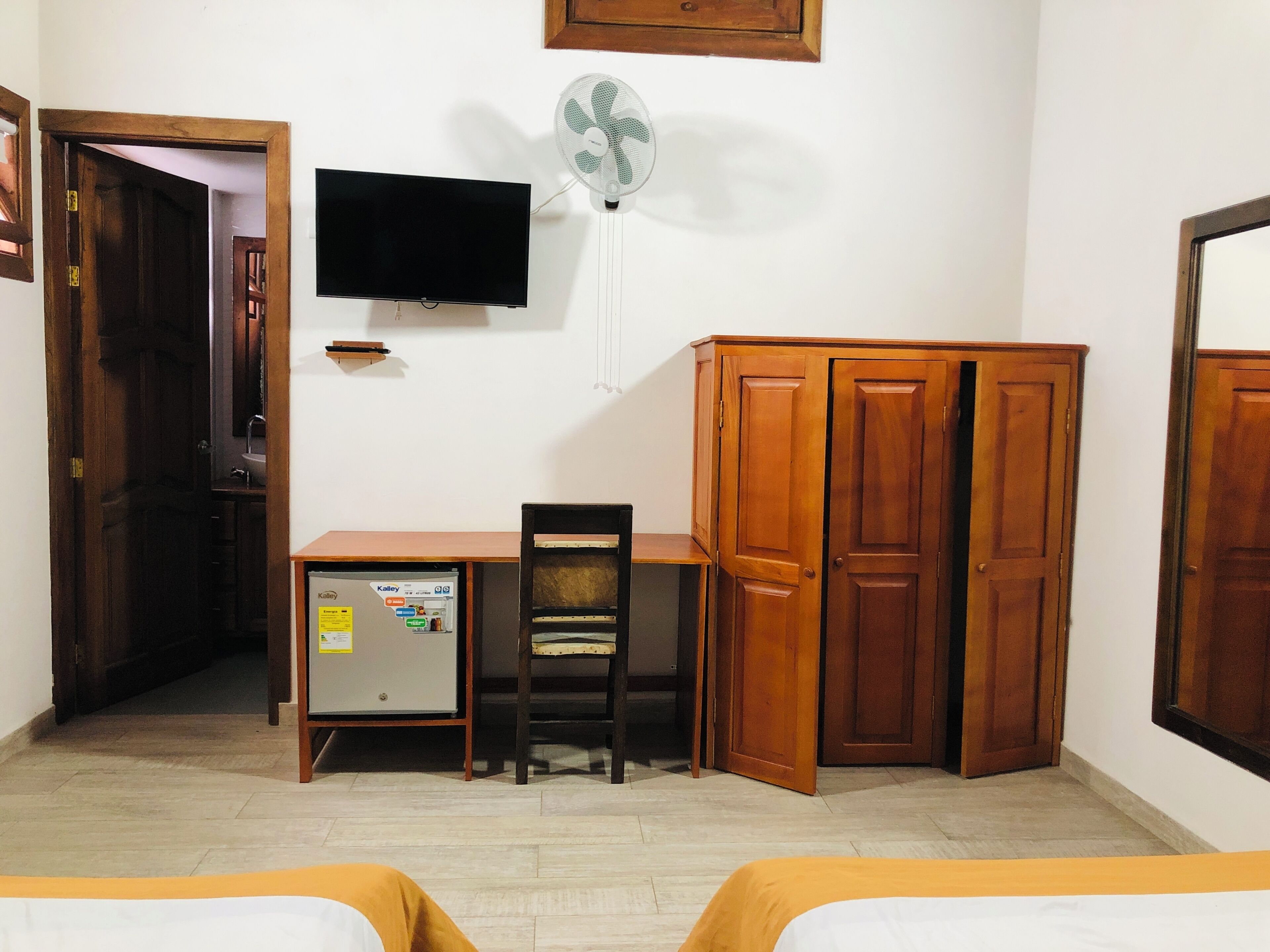 Une pièce comprenant un bureau, une chaise, une armoire, un lit et un téléviseur.