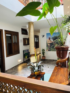 Recepció d'hotel amb sòl de marbre, mobles de fusta, plantes en testos i un quadre gran a la paret.