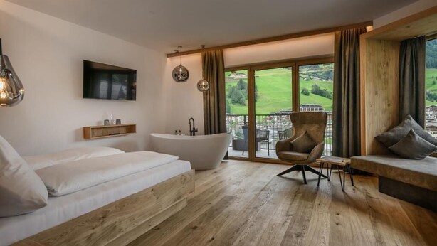 Een moderne badkamer met een badkuip, douche en een groot raam met uitzicht op groen.