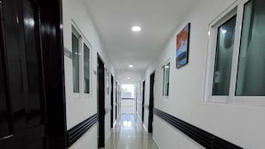 A long, narrow hallway with doors on both sides, a tiled floor, and a ceiling with recessed lighting.
