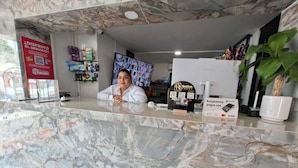 A marble reception desk with a digital screen, a refrigerator, and a sign indicating payment acceptance.