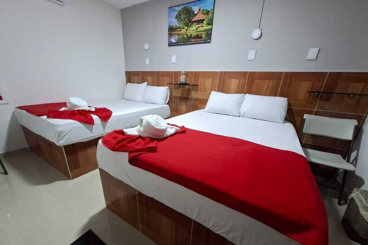 A hotel room with two beds, a wooden headboard, a small table, and a chair.
