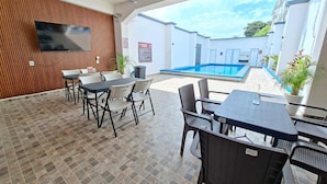 An outdoor patio with a pool, tables, and chairs.