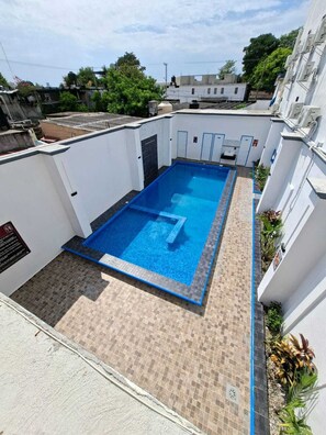 A rooftop swimming pool with a tiled deck, surrounded by white walls and some greenery. - Hotel Regina (Centla)