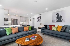 Ein modernes Wohnzimmer mit zwei Sofas, einem Couchtisch und einer Küche im Hintergrund.