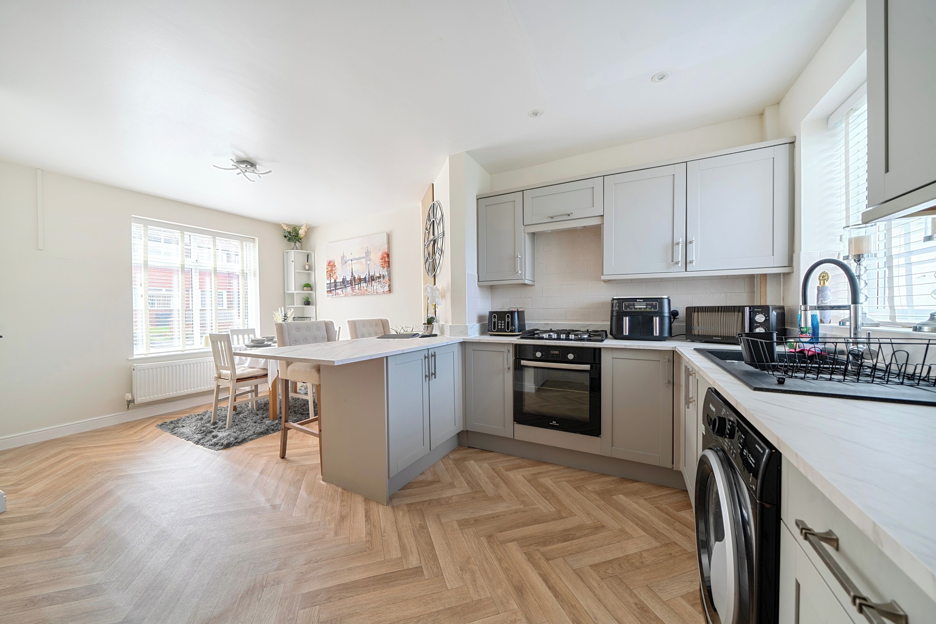 A modern kitchen with a central island, built-in oven, and dishwasher.