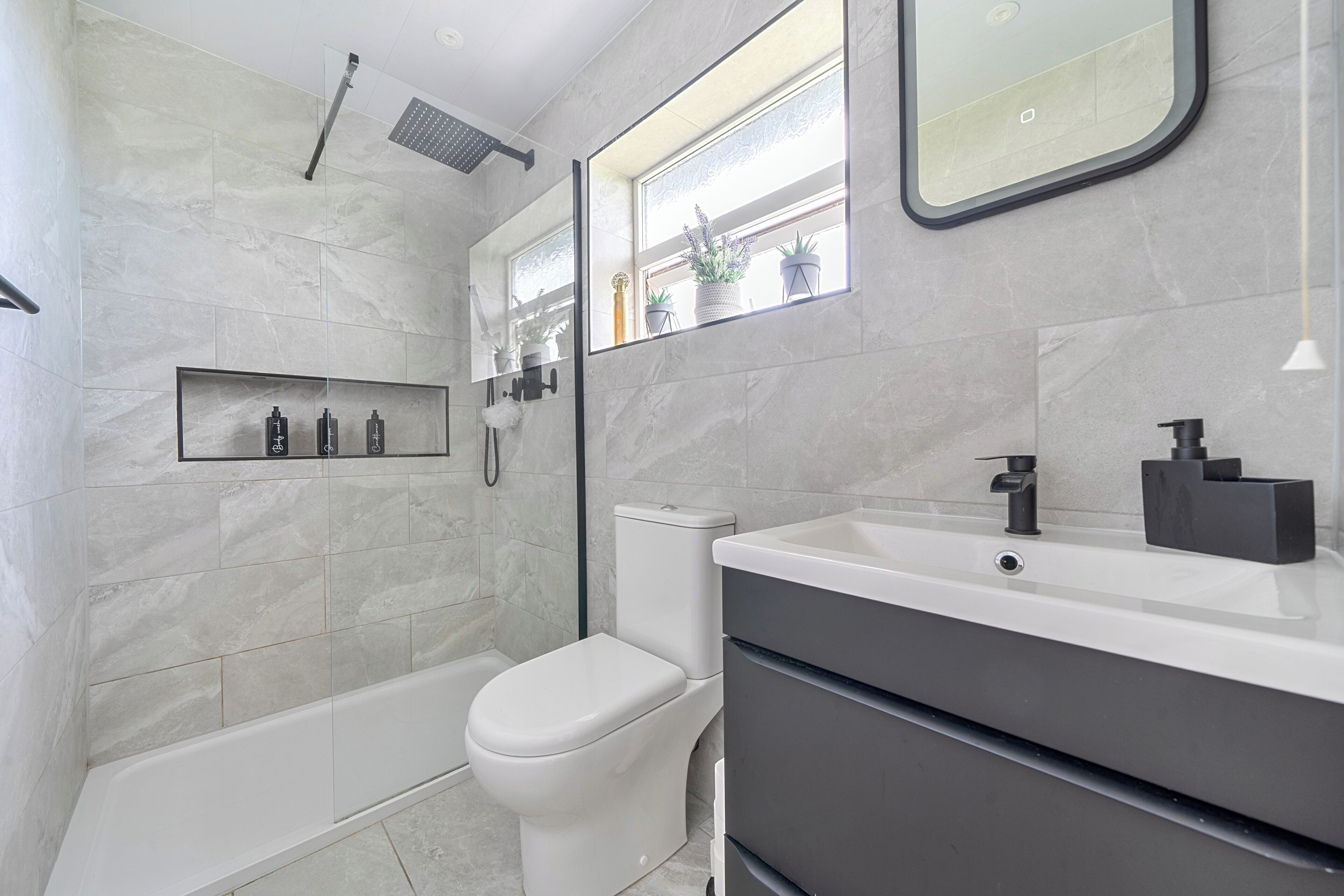 A modern bathroom with a bathtub, toilet, and vanity.