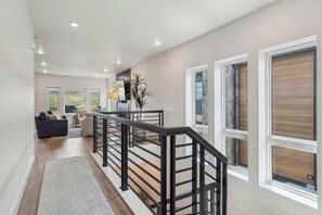 Ein modernes Interieur mit einer Treppe, einem Sofa und großen Fenstern.
