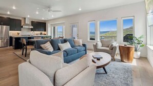 Uma sala de estar moderna com sofá, poltronas, mesa de centro e vista para o exterior.
