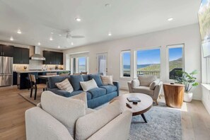 Ein modernes Wohnzimmer mit einer Couch, Sesseln, einem Couchtisch und Blick ins Freie.